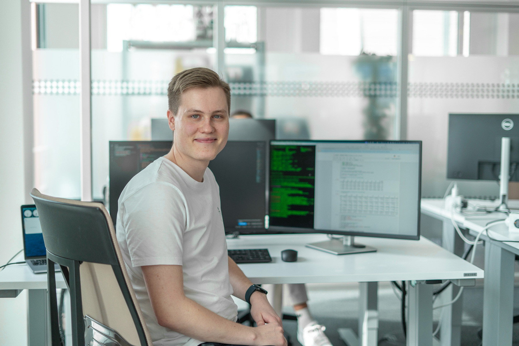 Valentin Müller sitz am Arbeitsplatz mit Laptop und zwei Bildschirme