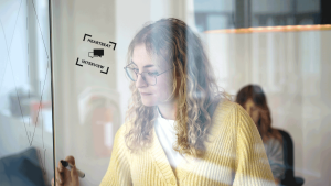 A female focussed person writing on a glass wall